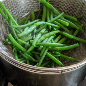 Blanched green beans in a colander.
