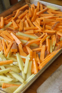 A sheet pan of oven fries, regular and sweet potatoes, ready to roast.