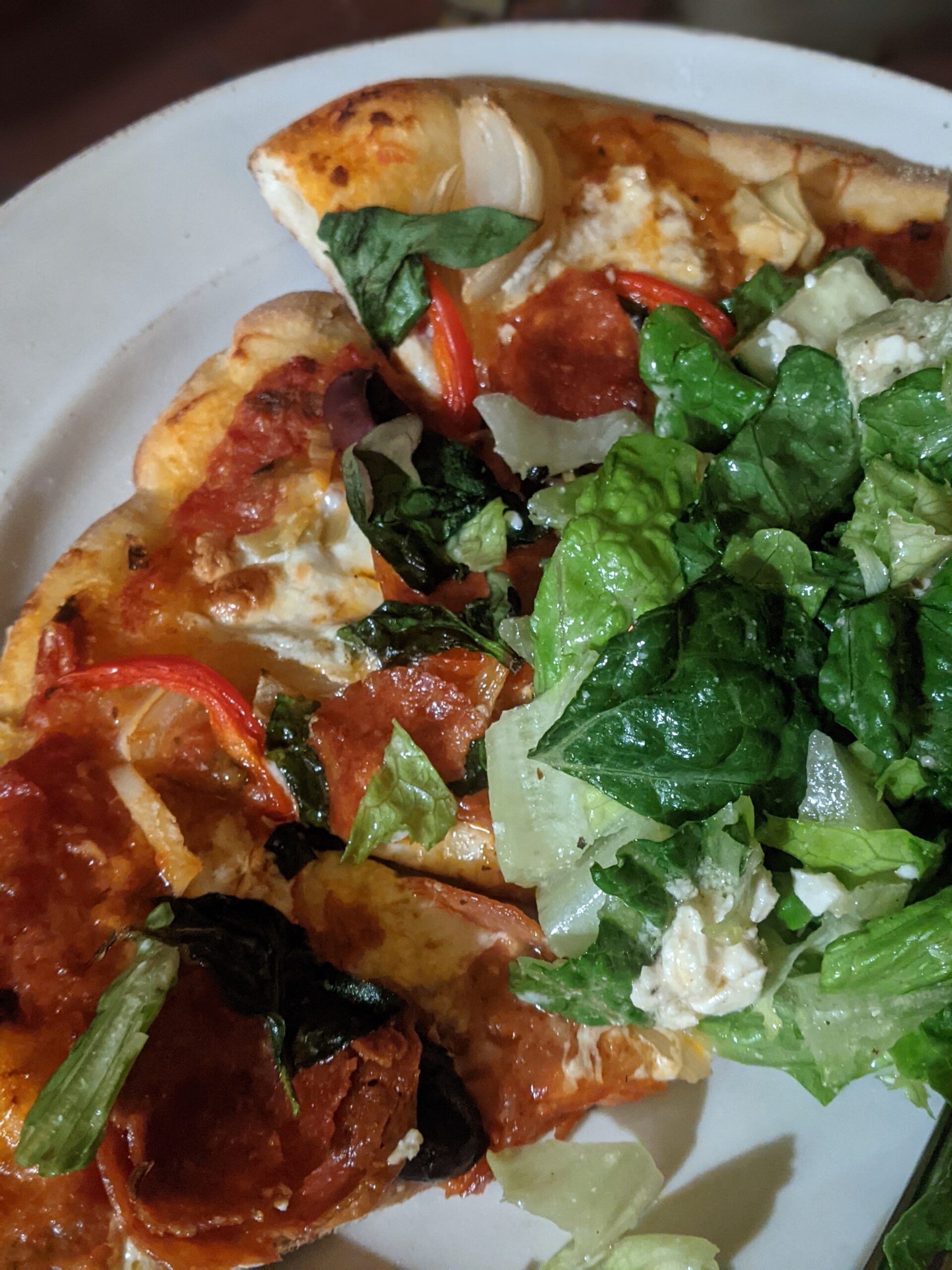 A plate of 3 pizza slices and a green garden salad.