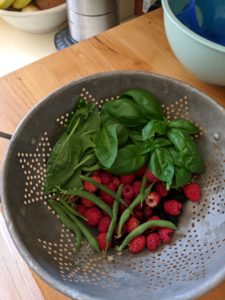 Harvested bowl of basil, raspberries, and green beans.