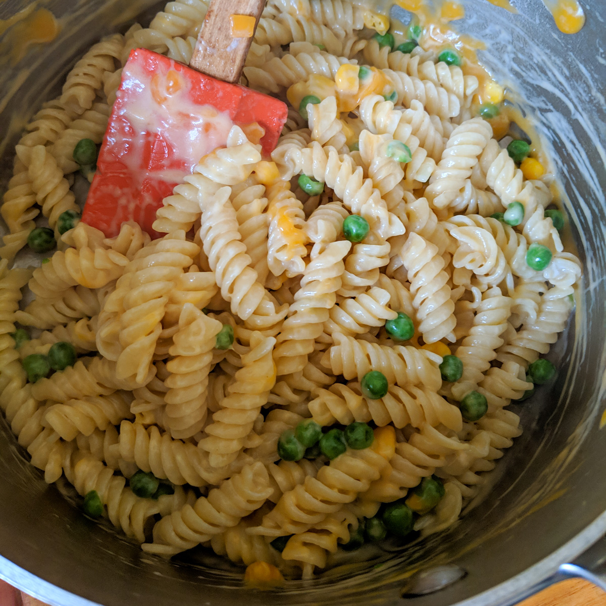 A variation of a pot of mac and cheese with rotini pasta, peas and corn.