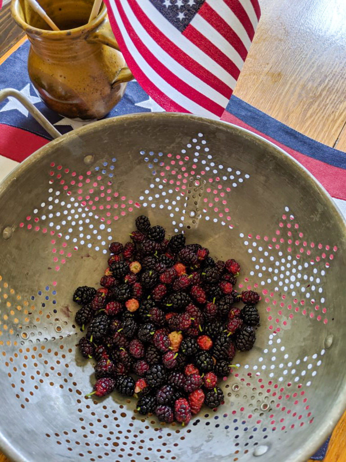 Bowl of Harvested Mulberries on the table with a flag for the 4th of July.