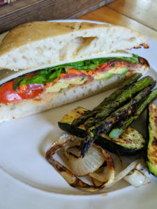 A slice of Italian Sub with giardiniera on a plate with grilled veggies.