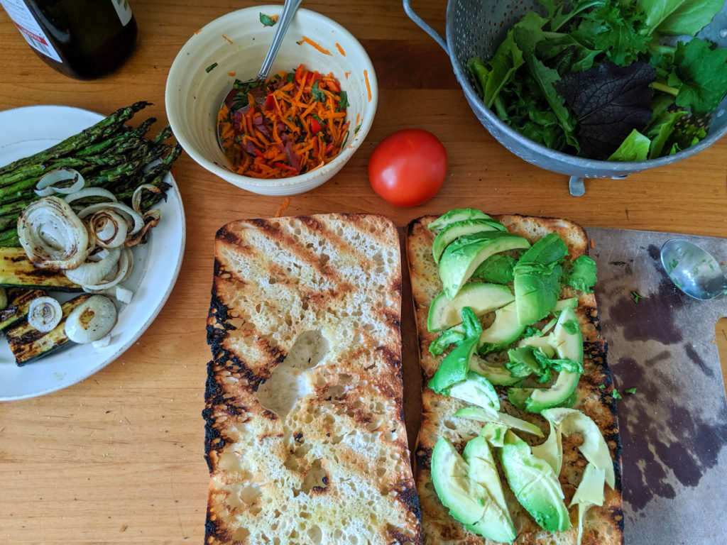 Grilled ciabatta topped with avocado, ready to build sandwich.