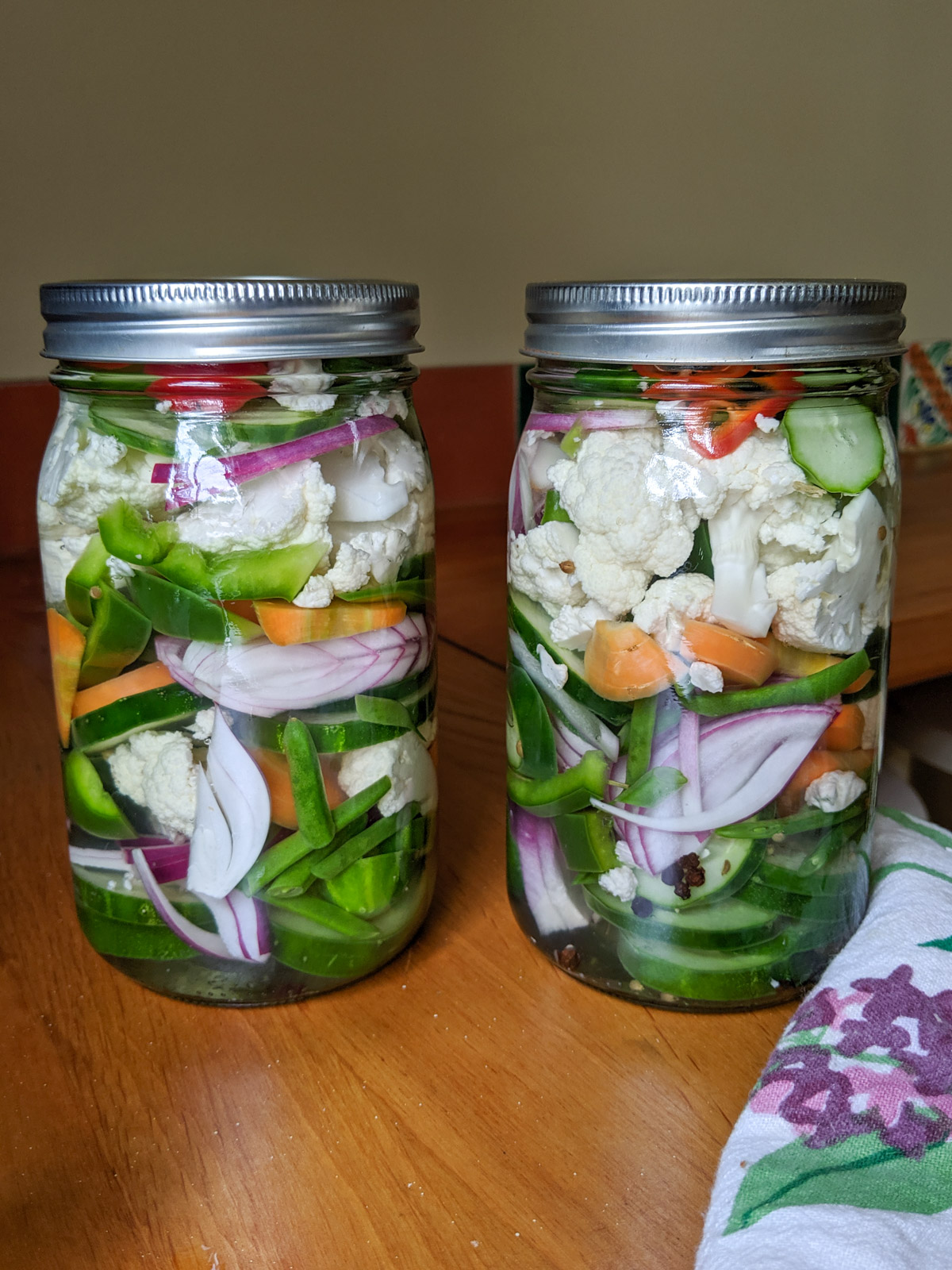 Two jars of giardiniera, pickled fresh garden vegetables.