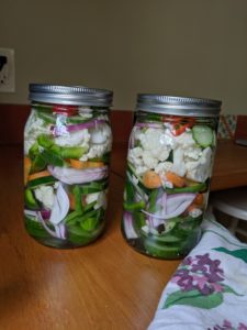 Two jars of giardiniera, pickled fresh garden vegetables.