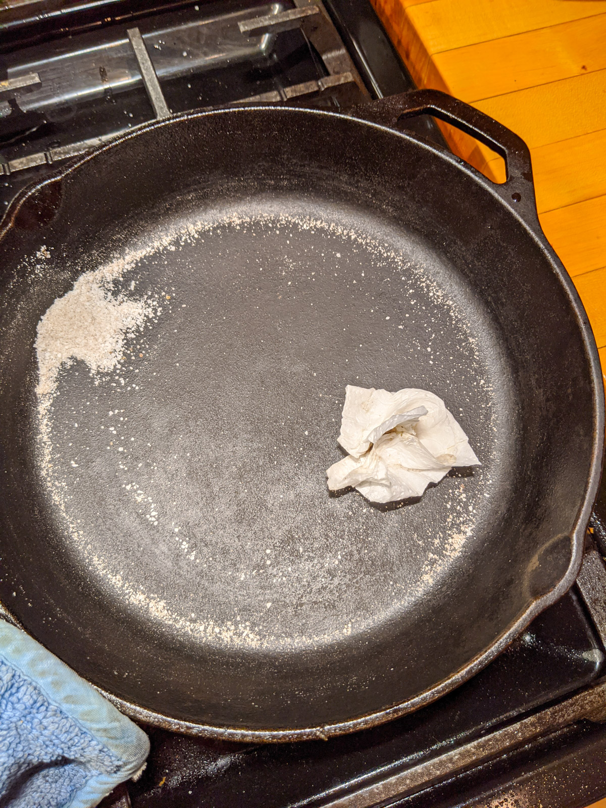 Cleaning a cast iron skillet with coarse salt and paper towel.