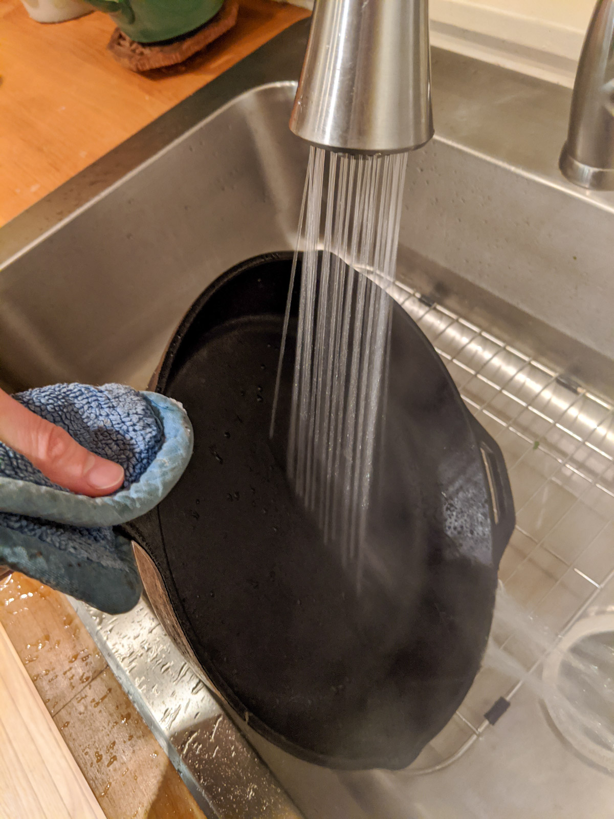 Spraying a cast iron skillet with water over the kitchen sink.