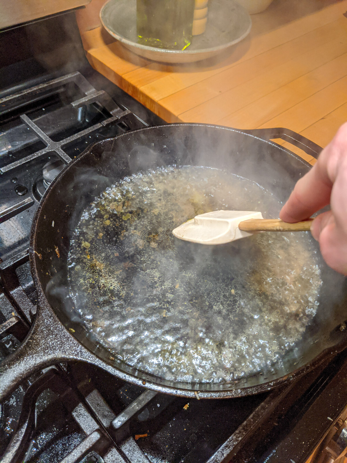 Deglazing a hot cast iron skillet with water to clean off grease and cooked on food.