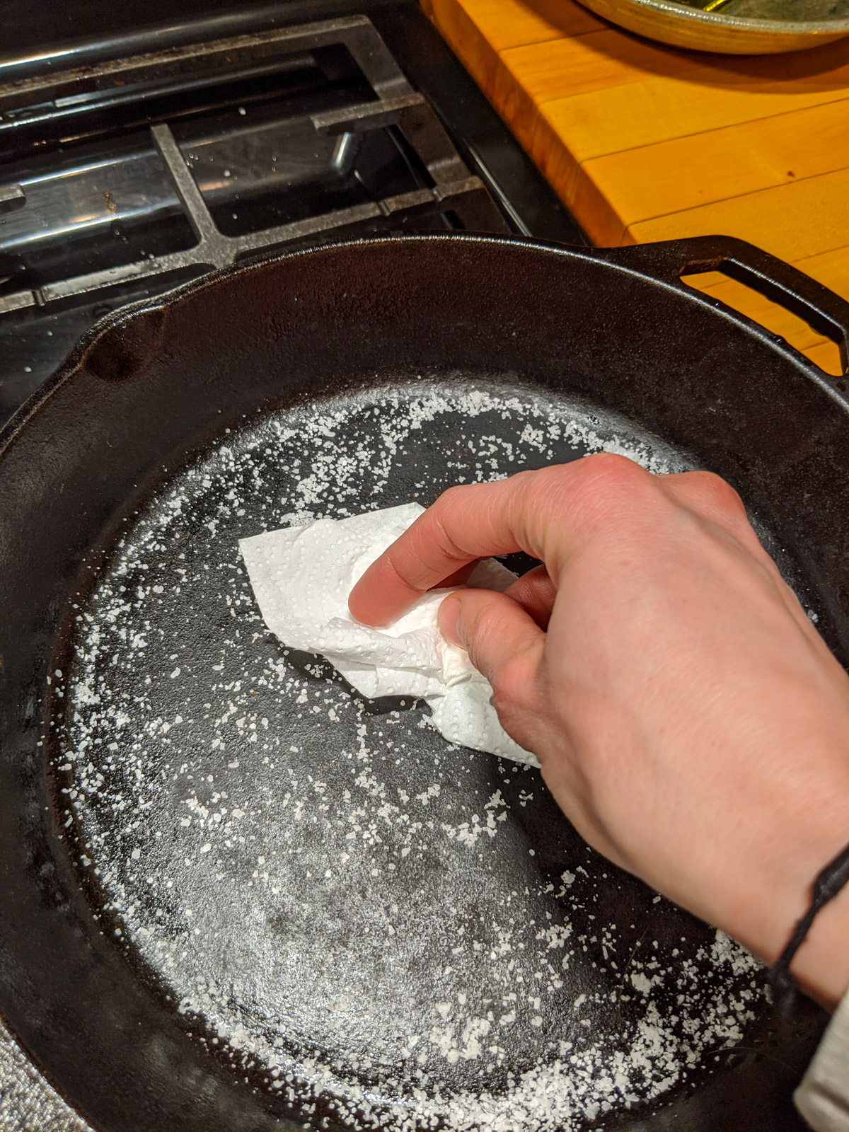 Rubbing a cast iron skillet with kosher salt with a paper towel.