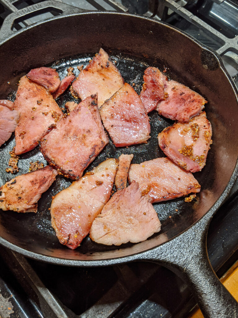 Sliced ham seared in a cast iron skillet.