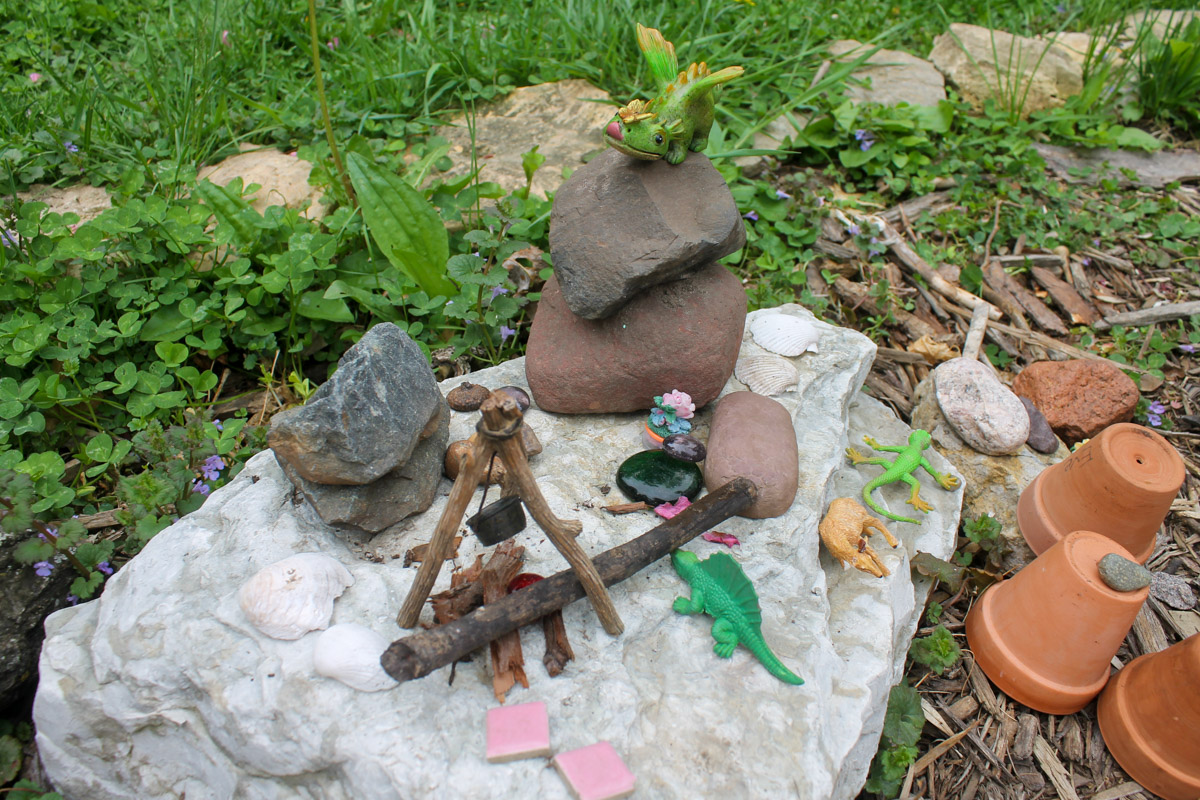 The kid's fairy garden with tiny figurines and animals on rocks.