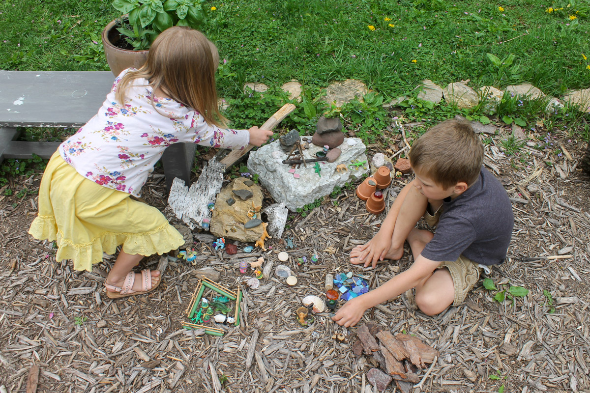 Kid's building a fairy garden next to a garden bench.