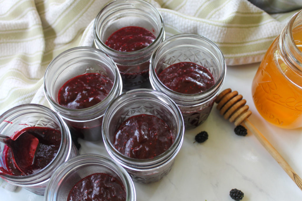 Finished jars of small batch freezer jam next to a jar of honey.