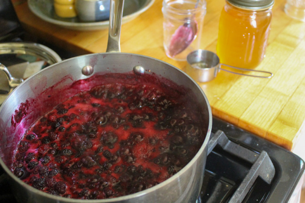Sauce pot of mulberry jam simmering on the stove.
