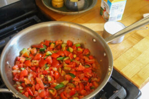 Sauteeing tomato and zucchini for creamy vegetable pasta.