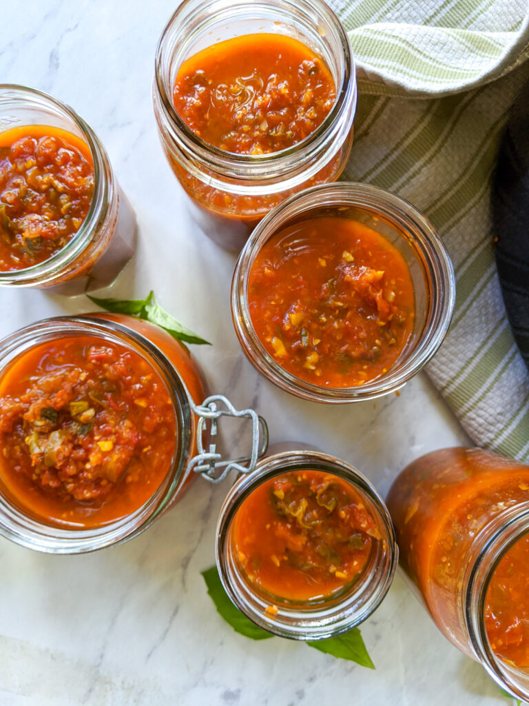 Top down view of filled jars of garden tomato sauce ready for the freezer.