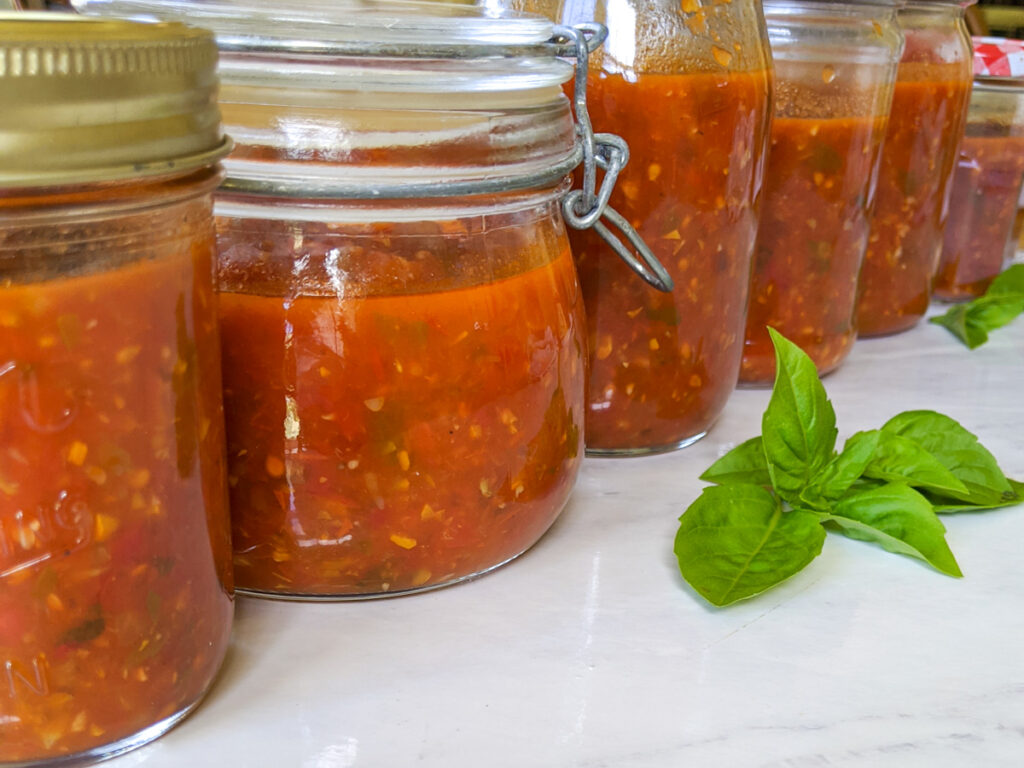 A row of finished jars of freezer marinara sauce.