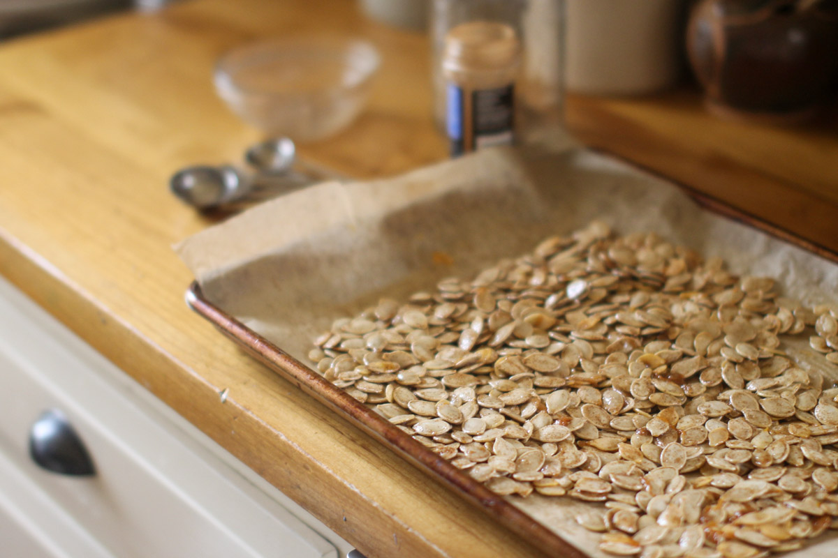 Pumpkin Seeds tossed with butter mixture and spread on a baking sheet with parchment paper.