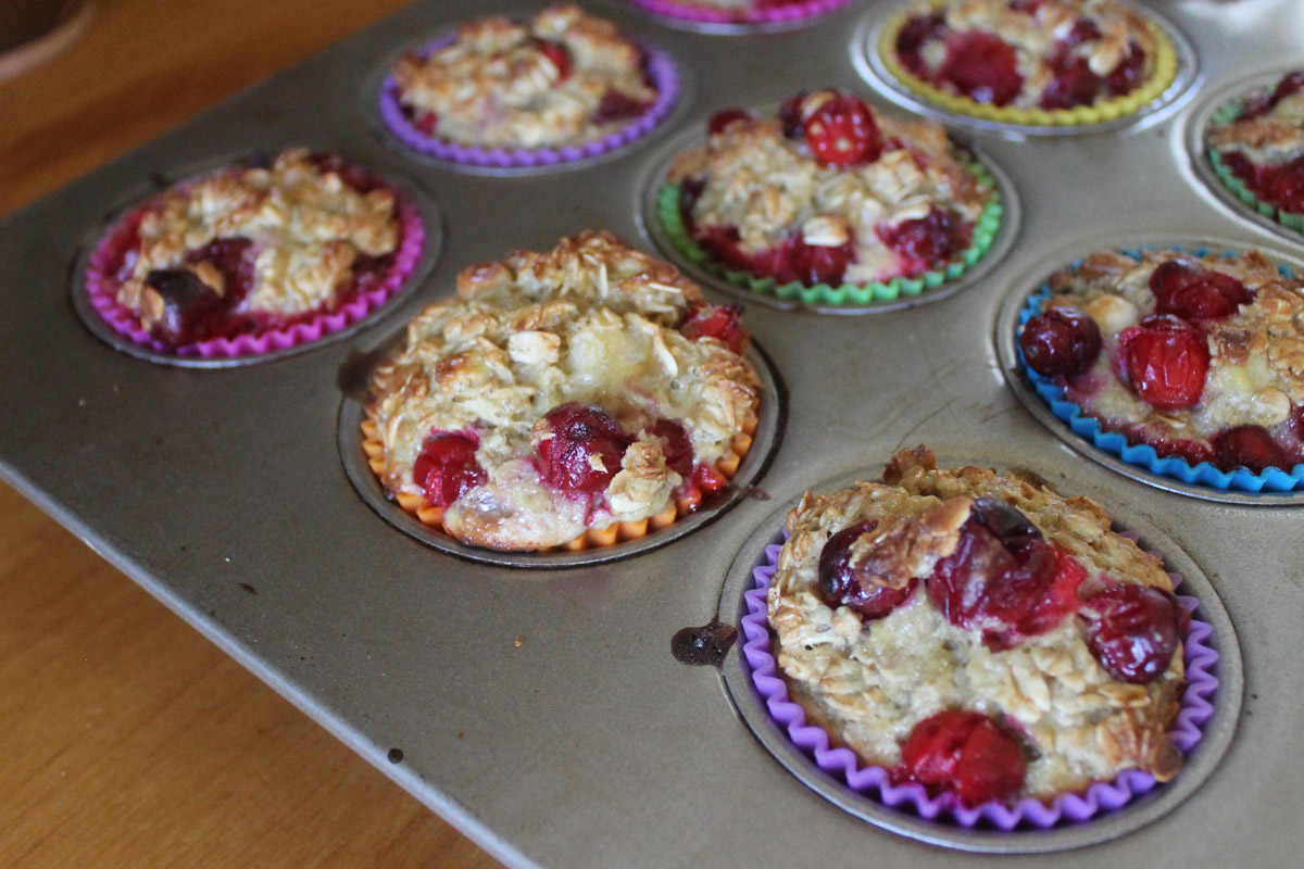 A muffin tin with baked cranberry oatmeal cups on the counter.