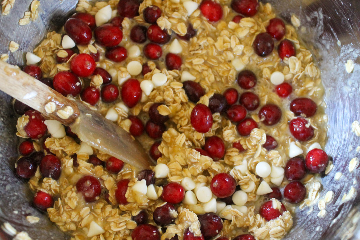 A bowl of batter for cranberry oatmeal cups with lots of bright red fresh cranberries.