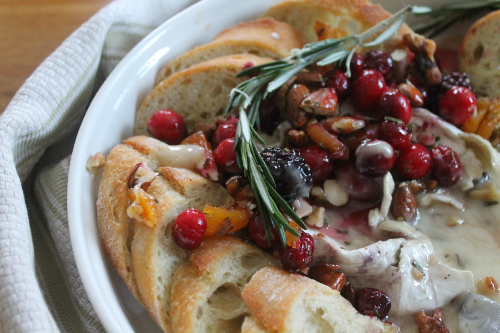 A closeup of the baked brie with fresh cranberries, nuts and rosemary.