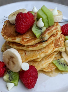 Christmas morning protein pancakes with red raspberries, green kiwi and white chocolate chips and banana