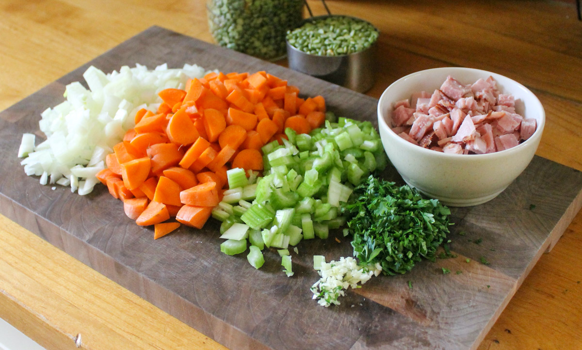 Chopped vegetables on a cutting board with all ingredients for split pea soup.