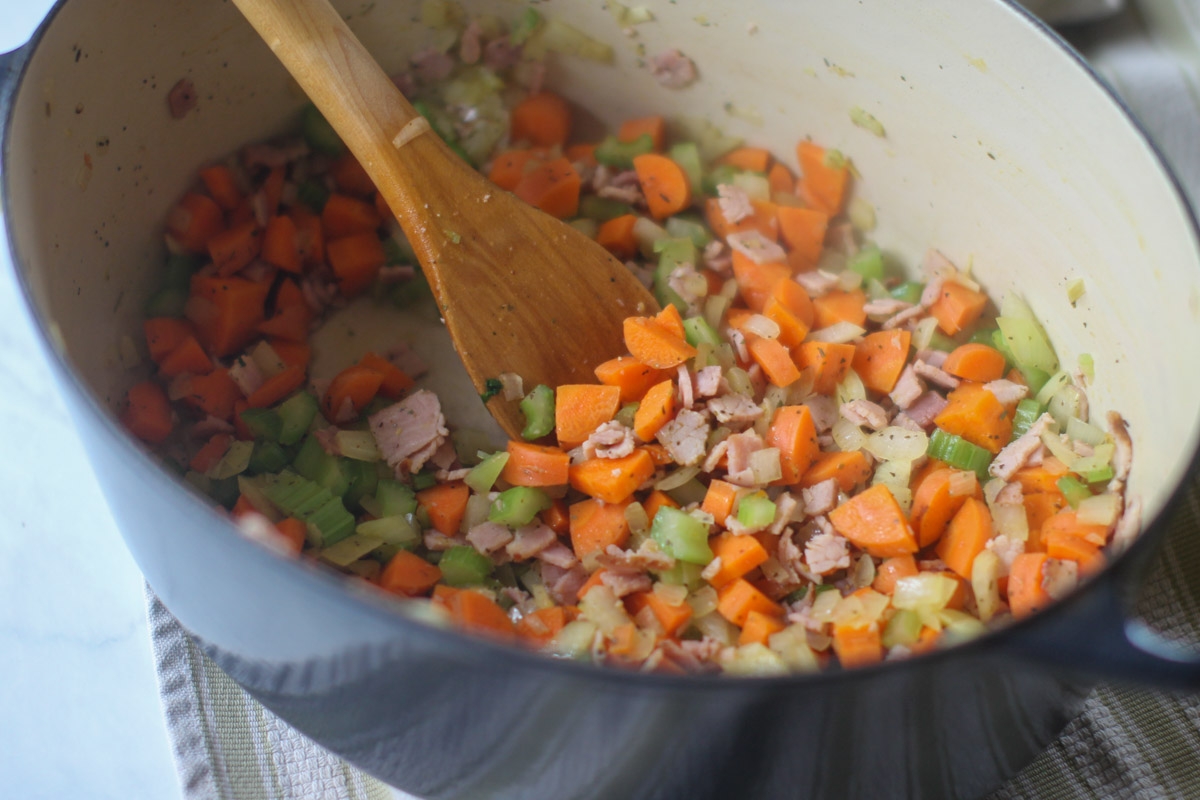The vegetables and ham cooking in a soup pot as the base for split pea soup.