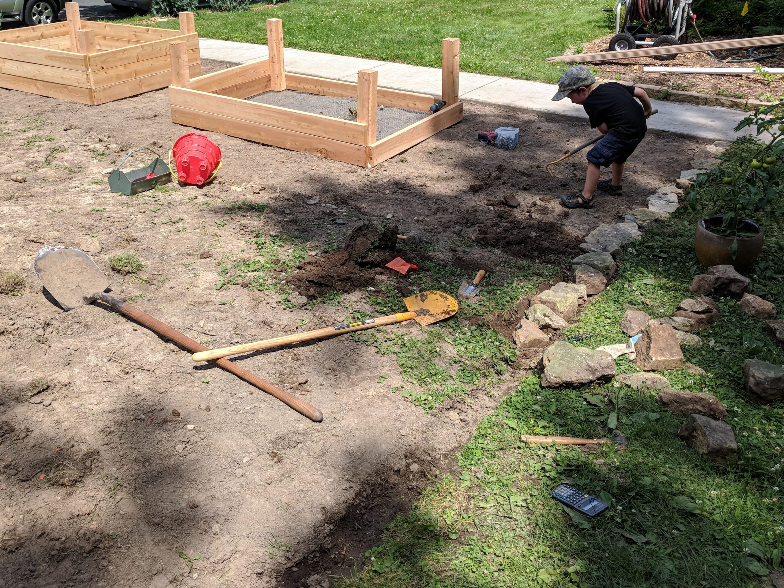 Child helping to dig the side for our raised bed garden.