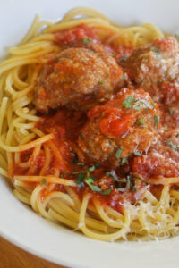 Close up of beef and Italian sausage meatballs in sauce over spaghetti.
