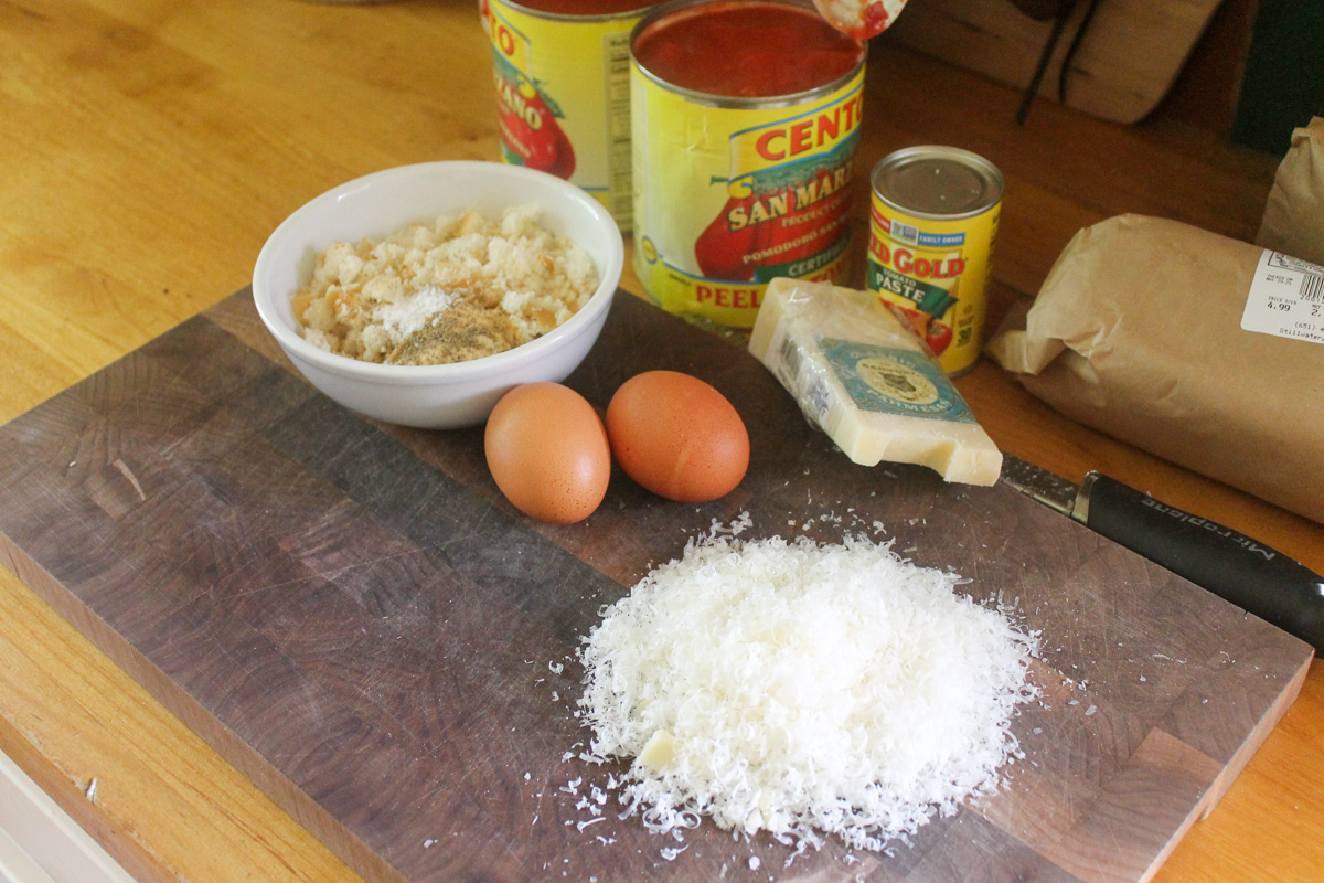 Ingredients on a cutting board for beef and Italian pork sausage meatballs.