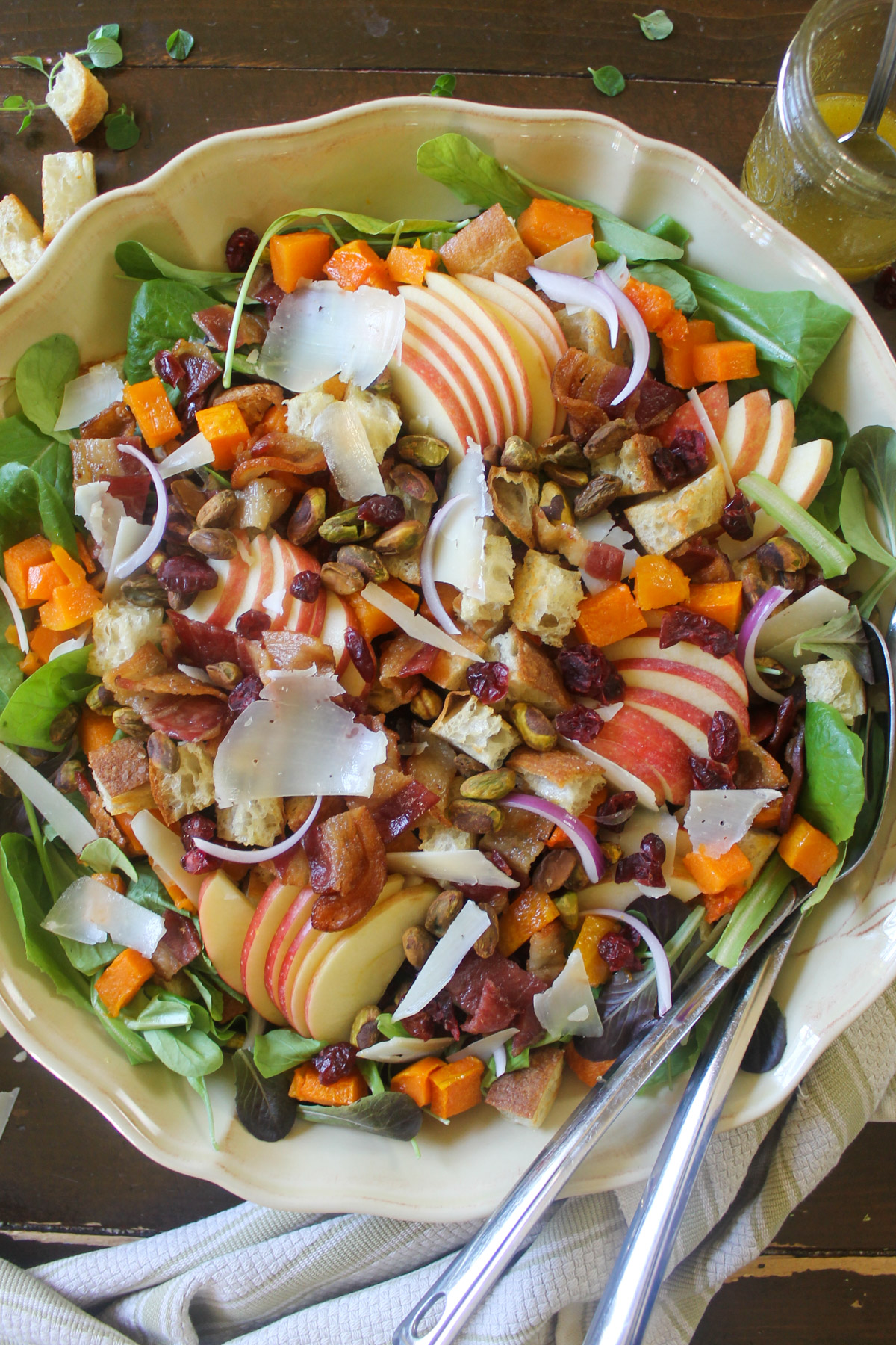 A large round platter of maple butternut squash harvest salad with serving spoons.