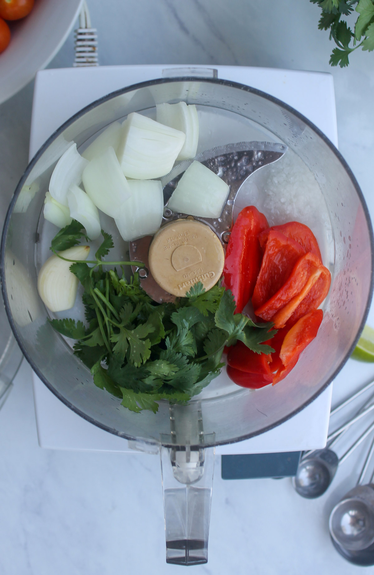 Onion, red bell pepper, garlic and cilantro in the bowl of a food processor.