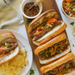 Grilled Italian Sausage with Giardiniera on buns on a wooden platter.