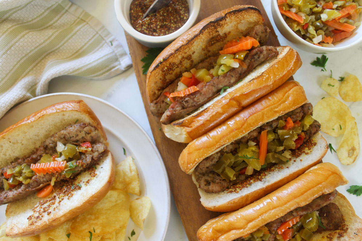 Grilled Split Italian Sausages with Giardiniera and Dijon Mustard served with potato chips.