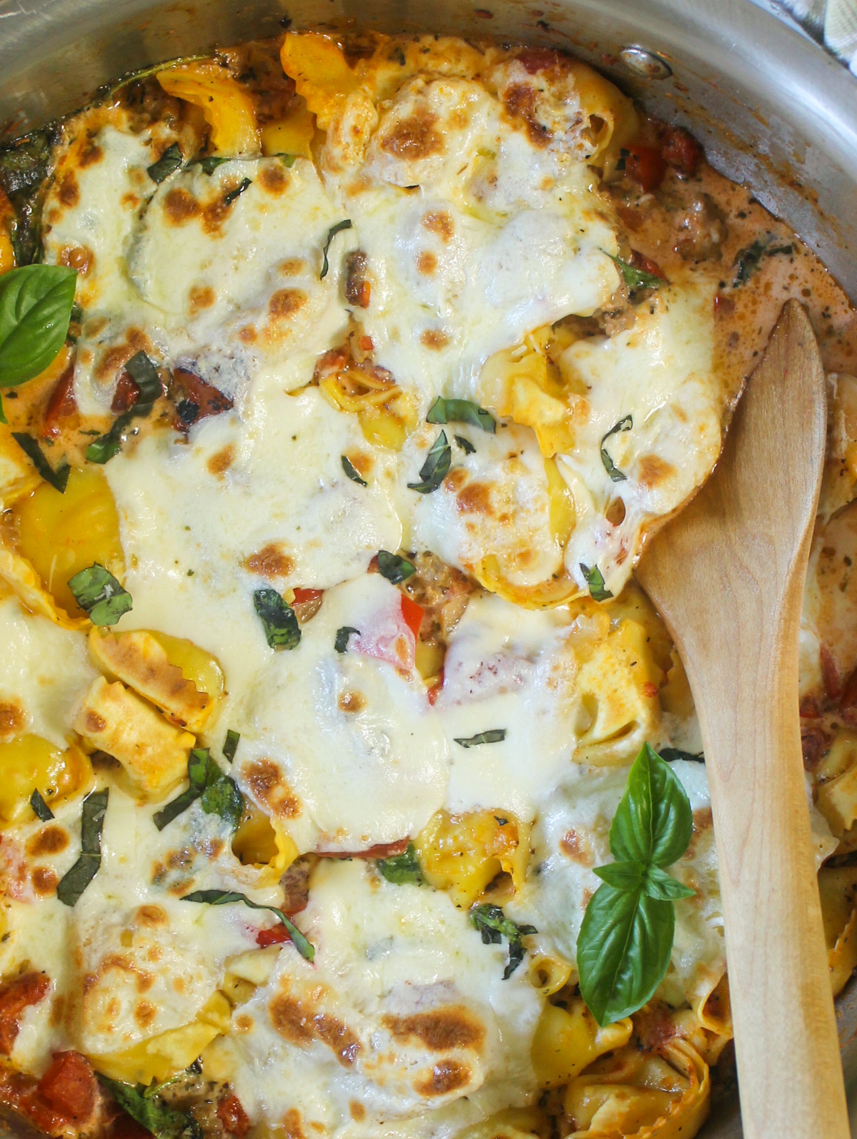 Baked Tortellini with Italian Sausage in a skillet with melty mozzarella and basil.