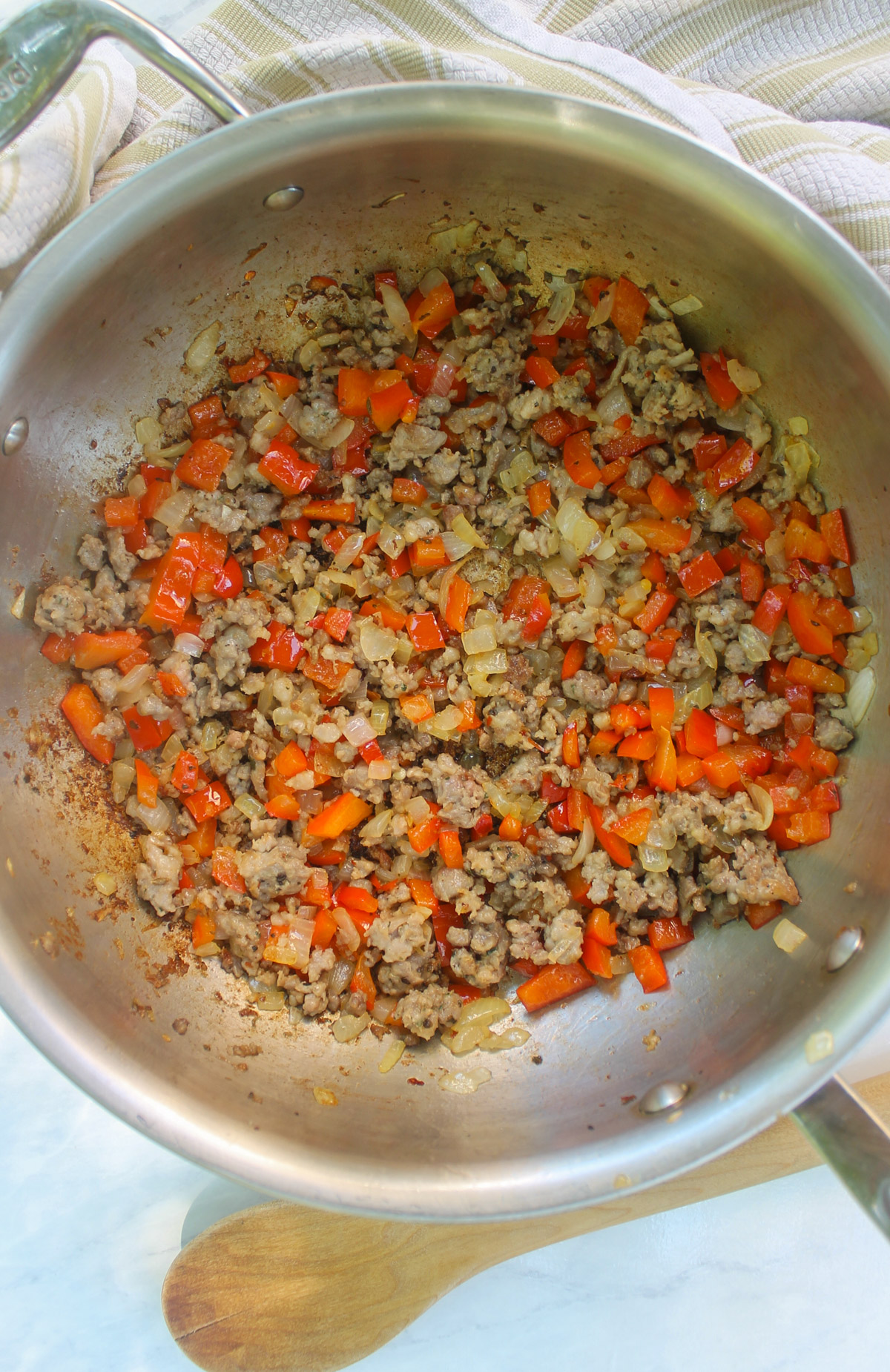 Fully browned Italian sausage in a skillet with onions and red bell peppers.