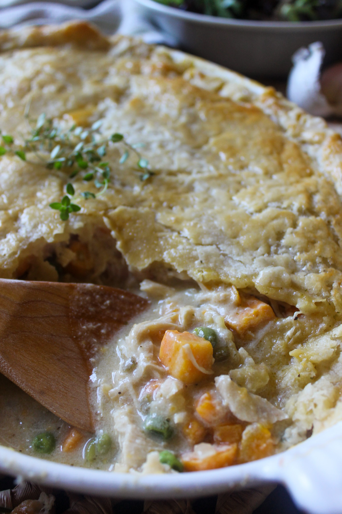 Chicken pot pie broken into with a wooden spoon showing the filling.