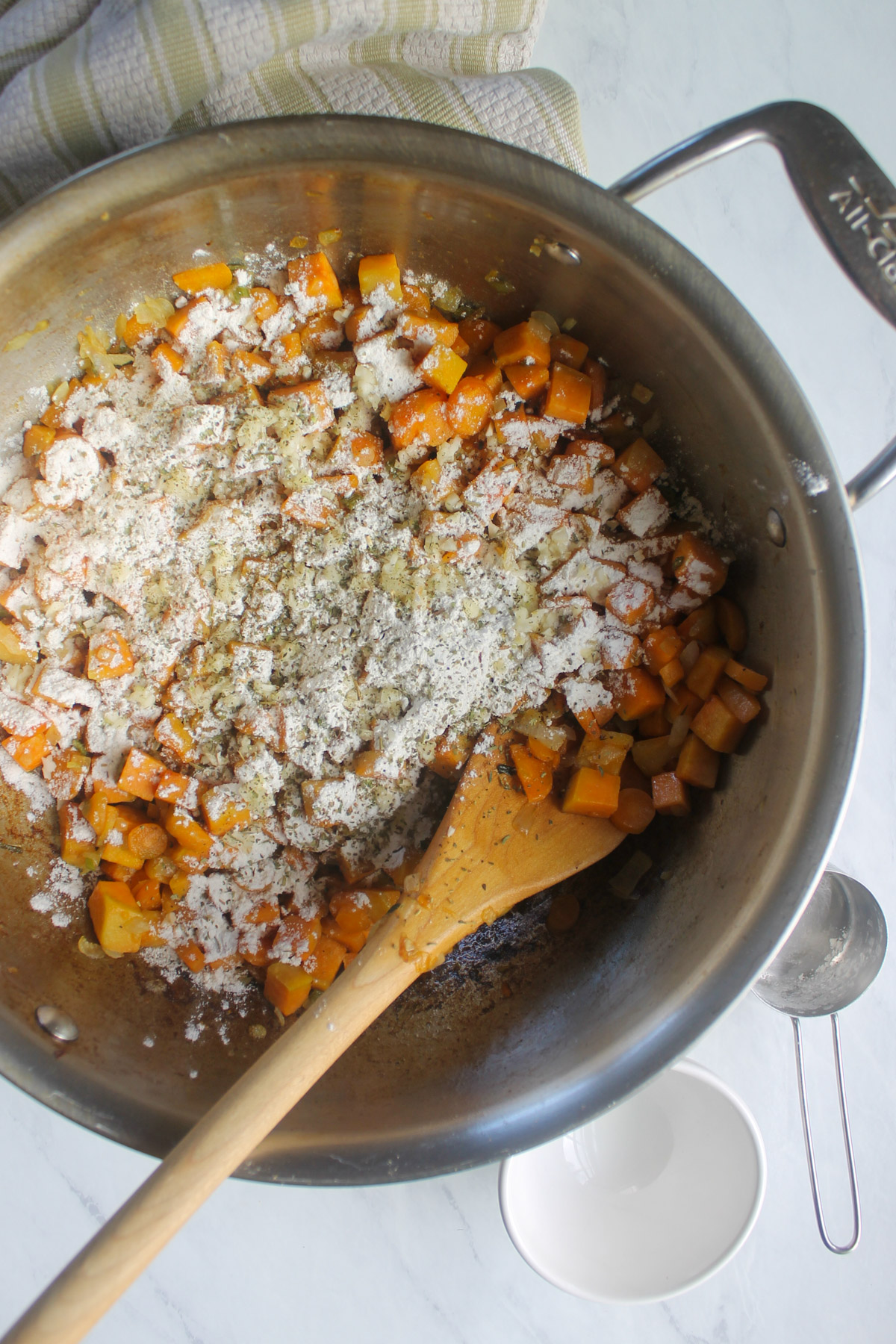 Adding flour, garlic and seasoning to vegetables in a skillet.