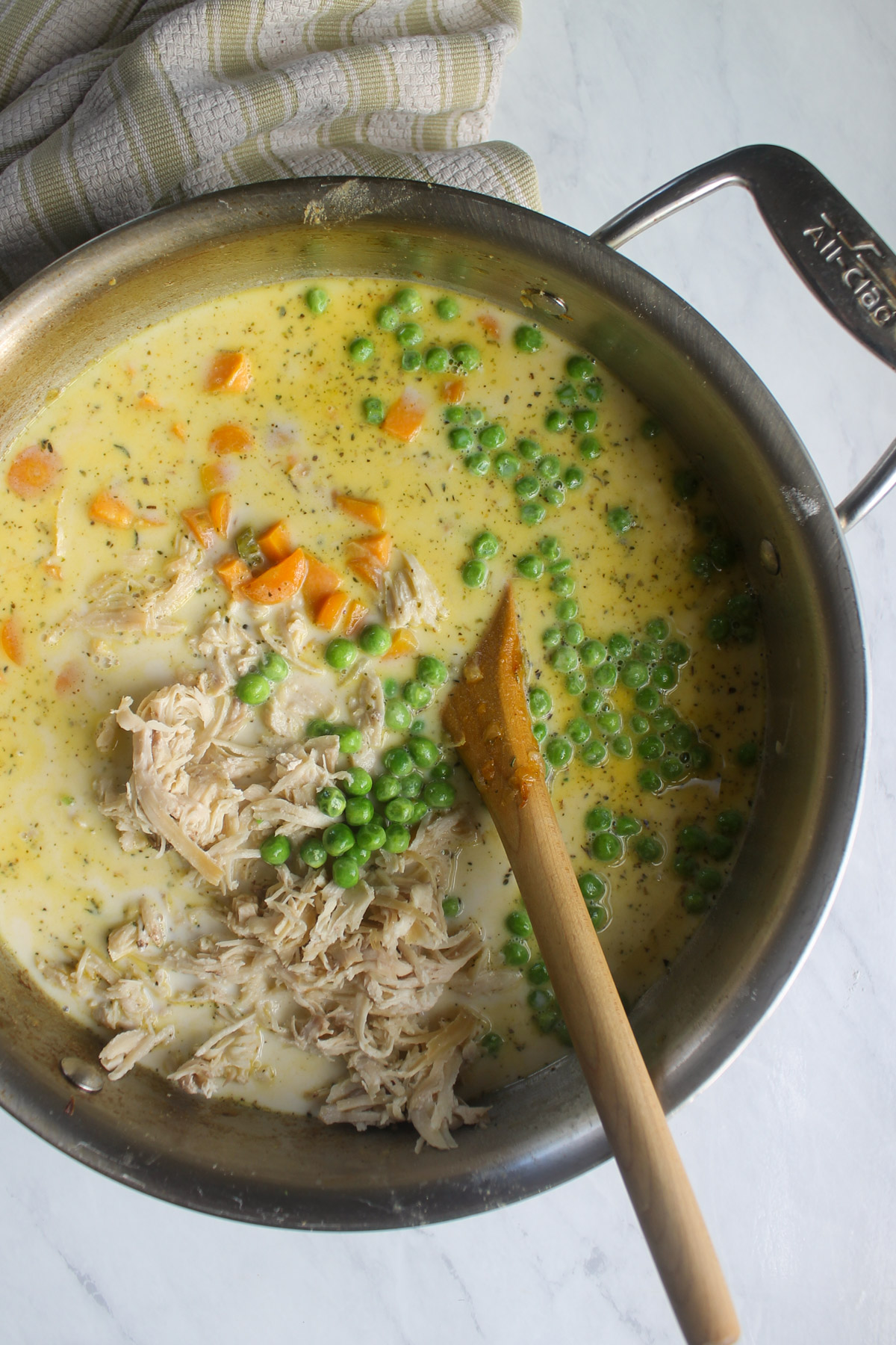 Adding chicken, peas, stock and milk to the skillet.