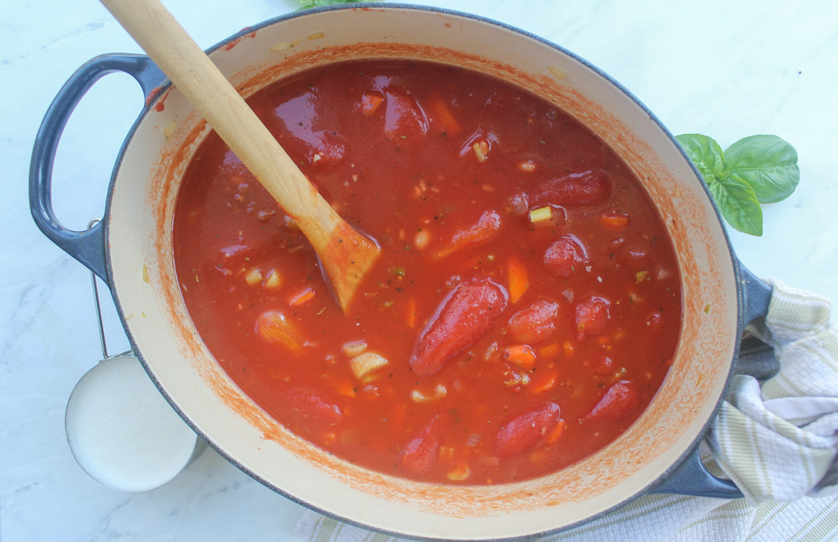 A pot of Tomato Soup with the veggies and canned tomatoes added but not yet blended.