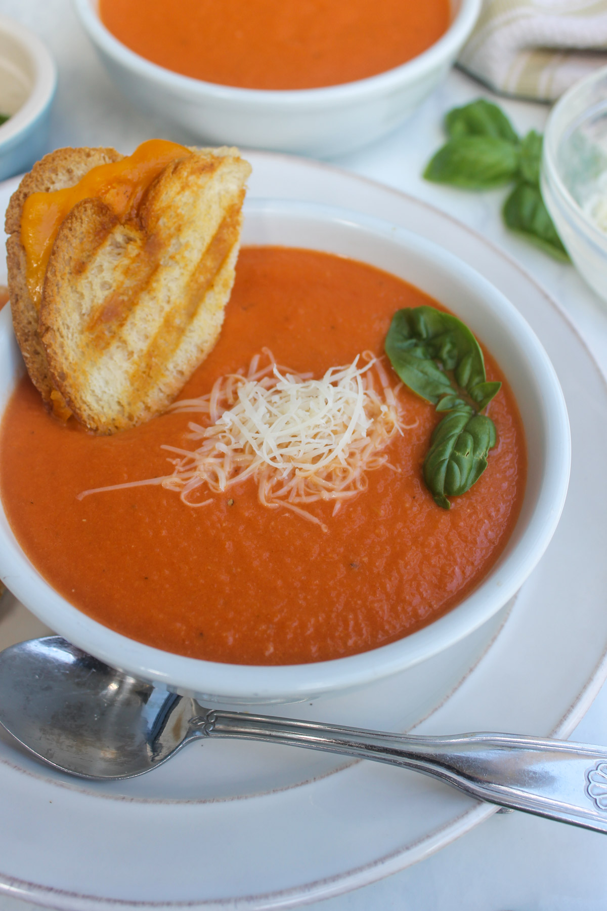 A bowl of Protein Tomato Soup with a grilled cheese sandwich dunked in it.