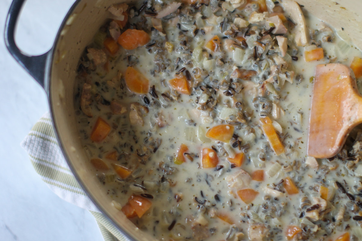 A Dutch oven full of hearty chicken wild rice soup.