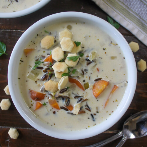 A white bowl of Minnesota chicken wild rice soup with crackers.