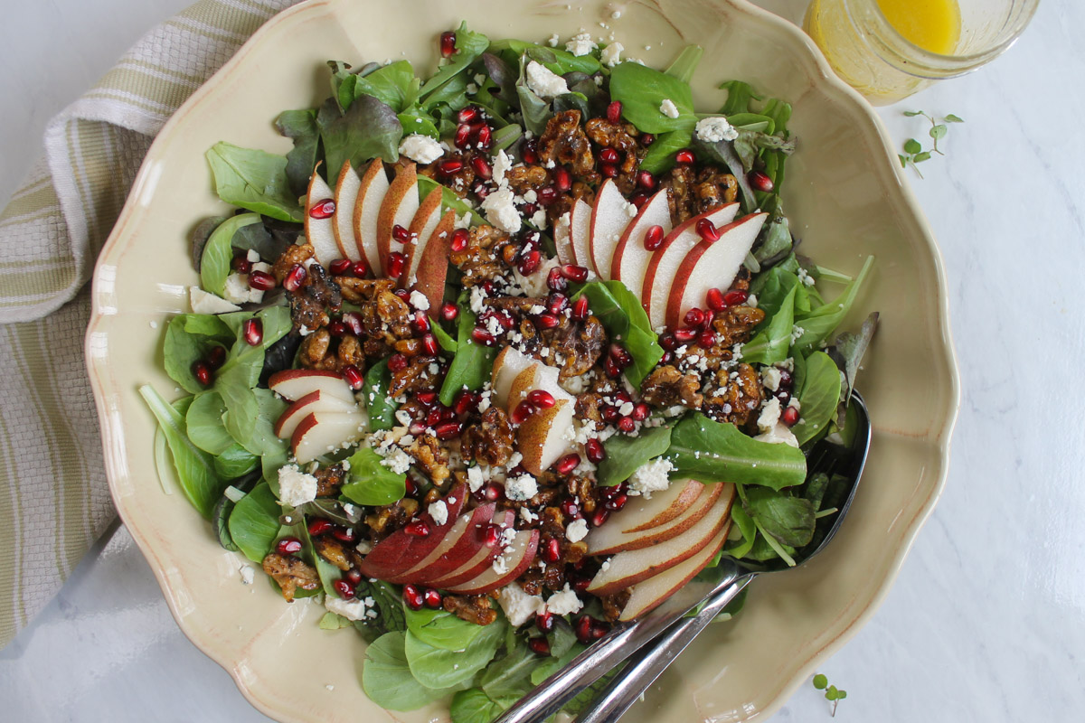 Pear and blue cheese salad with pomegranate seeds assembled on a serving plater.