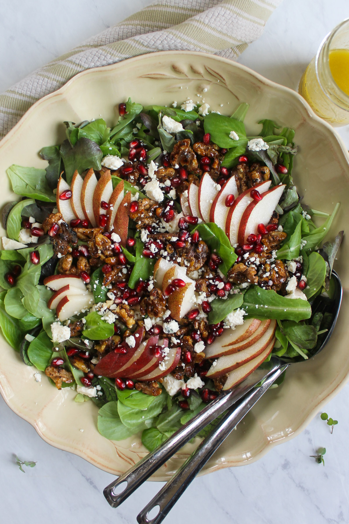 A serving dish of Pear and Blue Cheese Salad with Glazed Honey Walnuts and serving spoons.