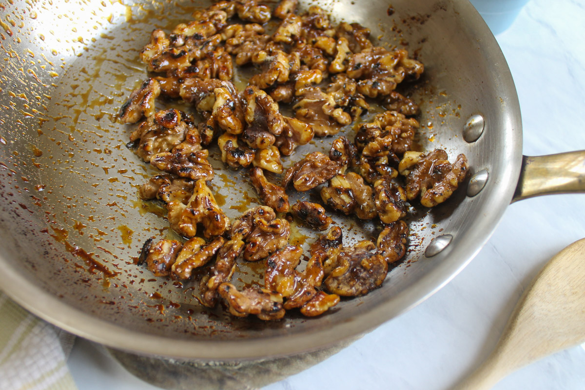 Glazed honey walnuts in a skillet.