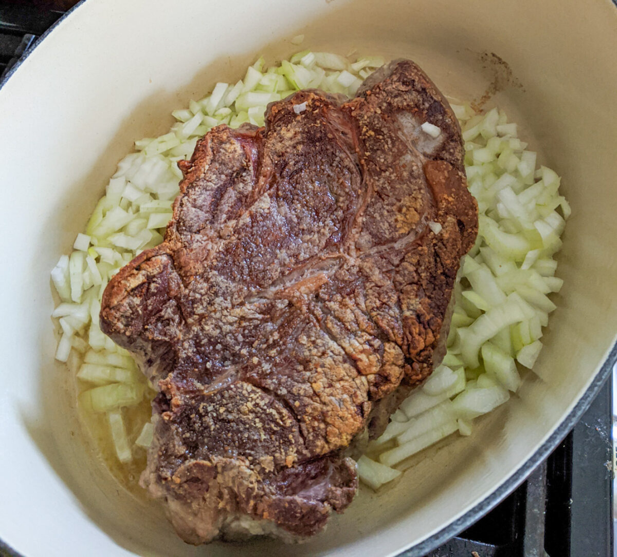 Seared beef roast in a Dutch oven with onions.