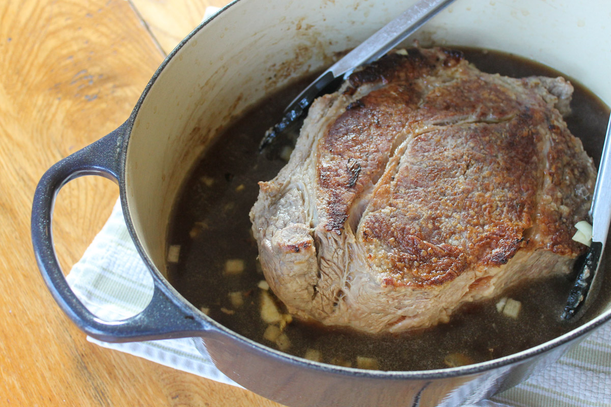 The seared beef roast in the Dutch oven with beef stock.